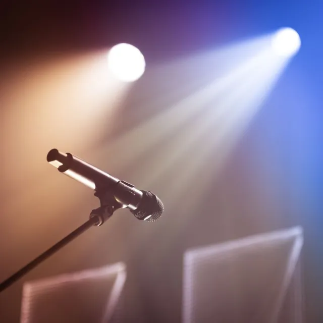 Micrófono en un escenario iluminado por focos antes de un concierto