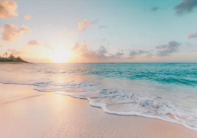 Playa de arena al atardecer con el mar en calma