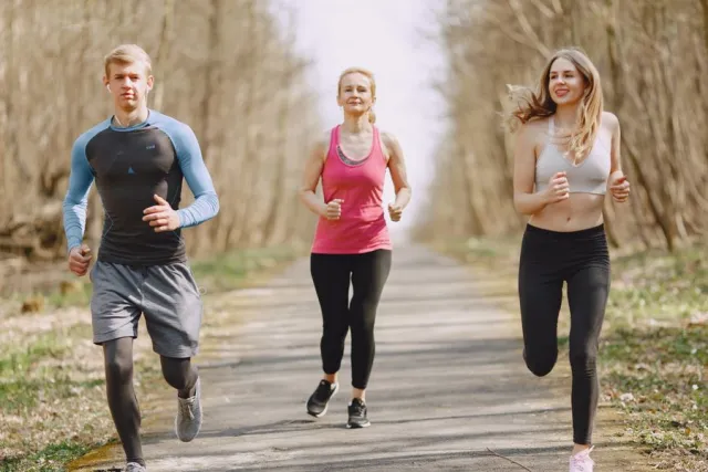 Tres personas corriendo juntas por un camino de un parque